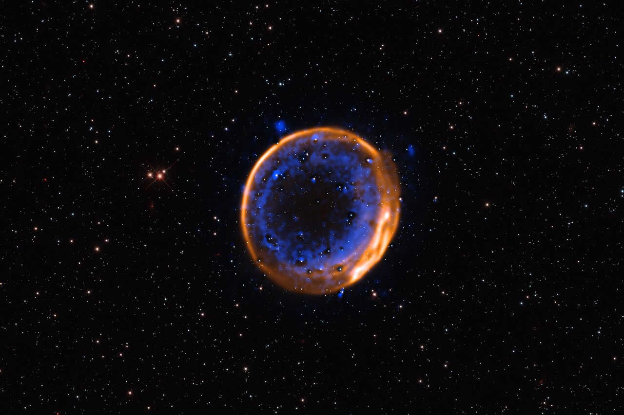 Questa immagine, acquisita con il Very Large Telescope (VLT) dell'ESO, mostra il resto di supernova SNR 0509-67.5. Si tratta dei resti in espansione di una stella esplosa centinaia di anni fa in una doppia detonazione: la prima prova fotografica che le stelle possono morire con due esplosioni. I dati sono stati acquisiti con lo strumento Multi-Unit Spectroscopic Explorer (MUSE) del VLT. MUSE consente agli astronomi di mappare la distribuzione di diversi elementi chimici, mostrati qui in diversi colori. Il calcio è mostrato in blu ed è disposto in due strati concentrici. Questi due strati indicano che la stella, ormai morta, è esplosa con una doppia detonazione - Crediti: ESO/P. Das et al. Stelle di sfondo (Hubble): K. Noll et al.